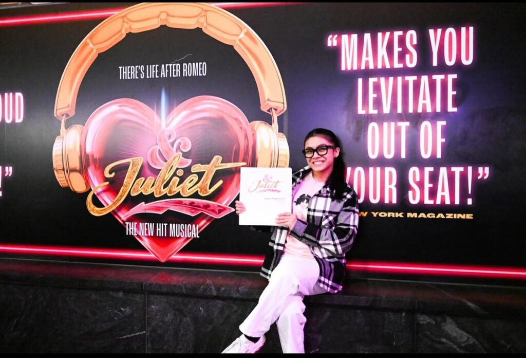 Dancer holding contract in front of poster of show she's joining.