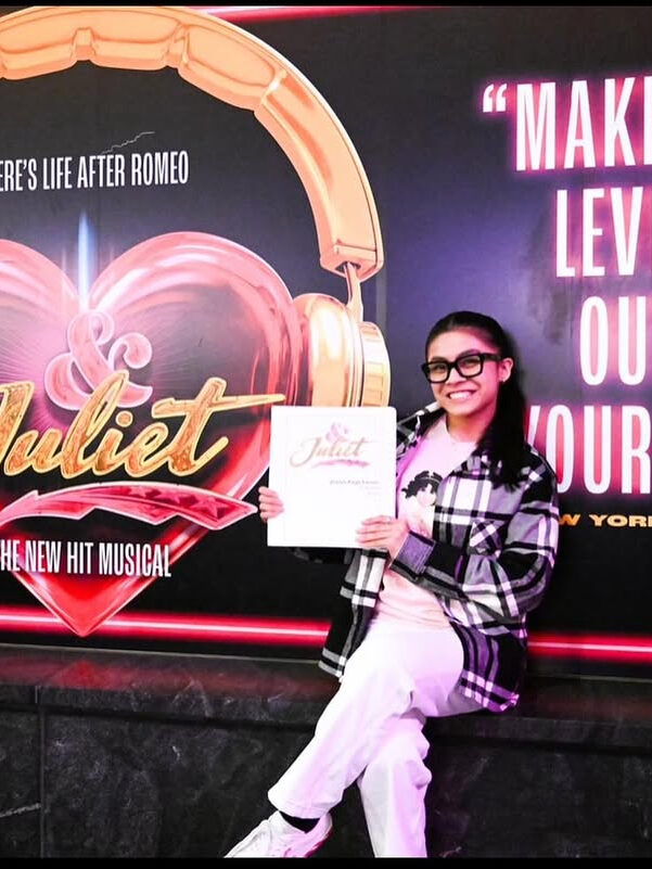 Dancer holding contract in front of poster of show she's joining.